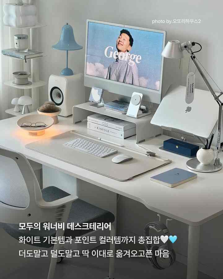 白を基調としたホームオフィス、清潔感のある白いデスクとモニター、青色のアクセントランプや小物が調和した雰囲気のあるインテリア