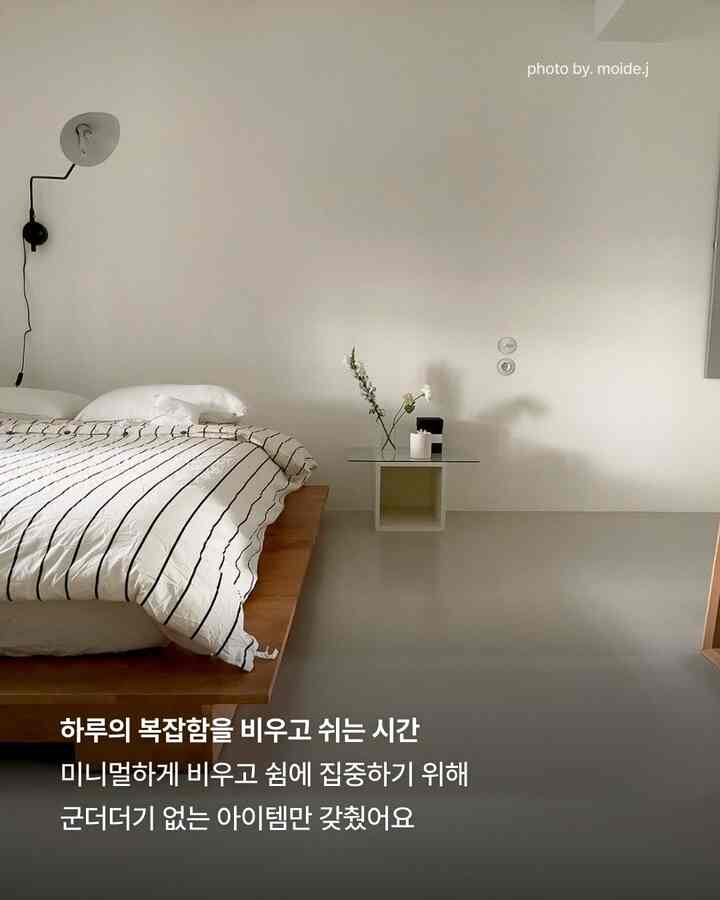 白と木目調が調和したミニマルな寝室、木製ベッドフレームとストライプの寝具が配置された落ち着いた空間