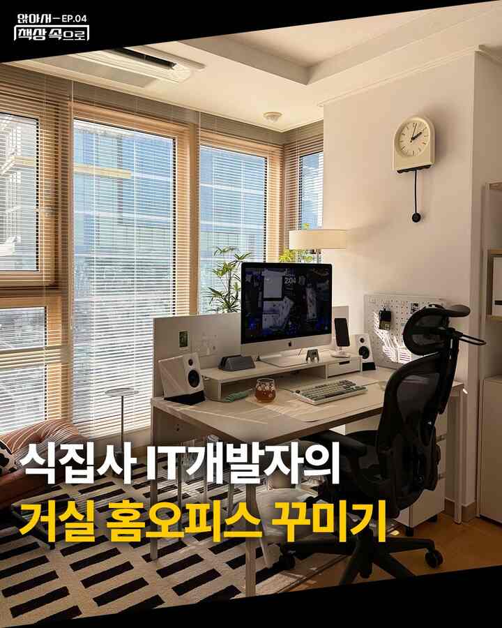 白とナチュラルカラーの明るいリビング兼ホームオフィス、広い窓際にデスクとオフィスチェアが配置された印象的な空間