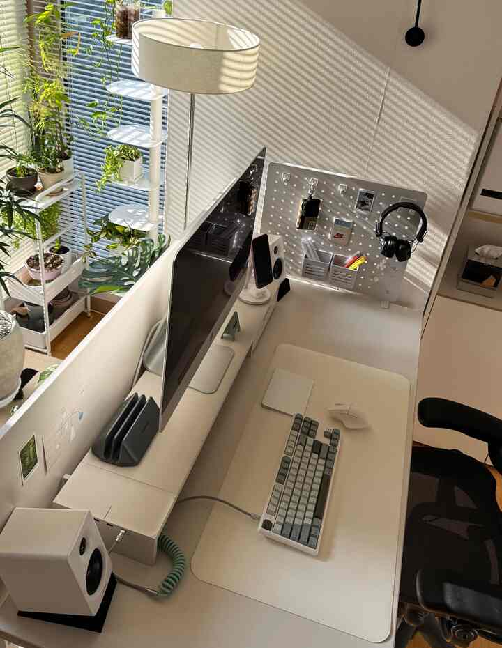 白とベージュのナチュラルトーンのホームオフィス、デスカーのモニタースタンドとエルゴノミクスマウス、メカニカルキーボードが配置された清潔感のあるデスク空間