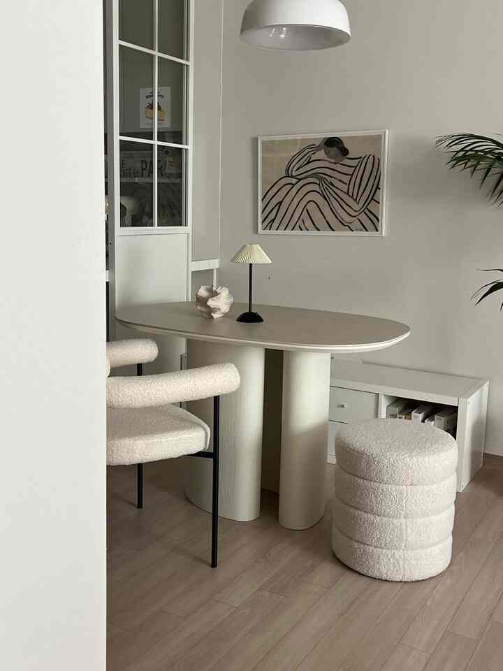 明るいホワイトとナチュラルな木目調のダイニング、楕円形のダイニングテーブルとブークレ素材のアームチェアが配置された雰囲気のあるインテリア