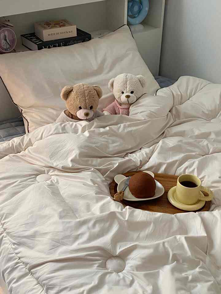 白と茶色のトーンの子供部屋のベッド、かわいいテディベアと木製トレイが配置された雰囲気のあるインテリア