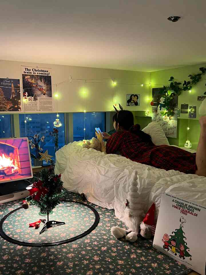 白と緑のトーンの低い天井のロフト寝室、クリスマスの飾りとストリングライトが配置され、雰囲気のあるインテリア