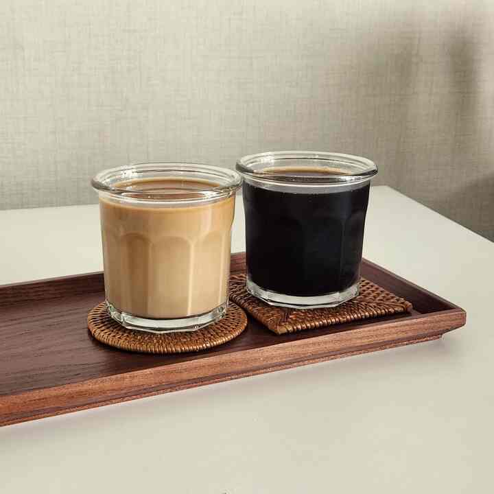 ナチュラルな木目調トレイにラタンコースターを敷いた2つの透明なグラスが配置されたおうちカフェの雰囲気あるインテリア