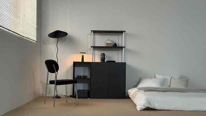 黒と白のトーンのワンルーム寝室、シンプルモダンなキャビネットとミッドセンチュリーモダンの椅子が配置された清潔感のあるインテリア