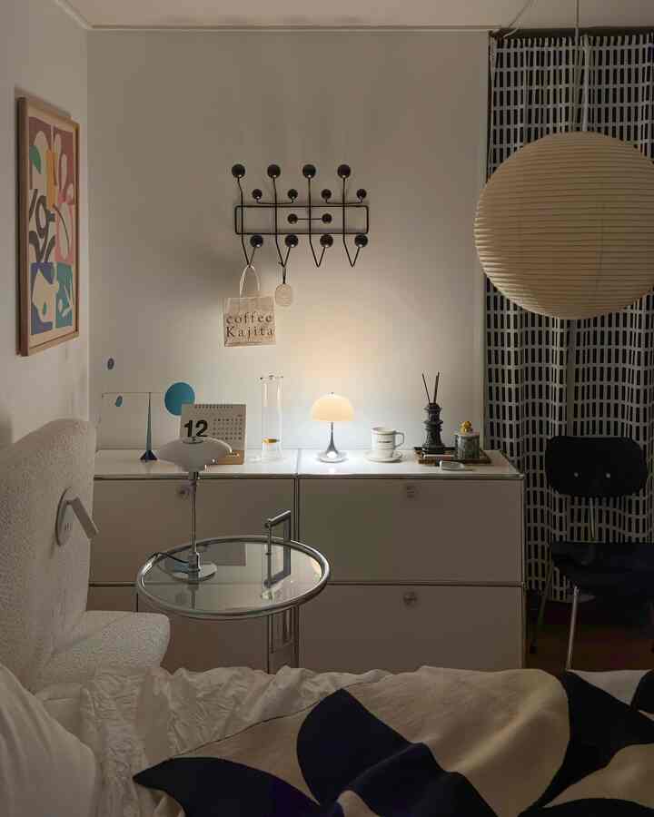 White and black toned bedroom featuring Louis Poulsen table lamp and minimal furniture with a cozy atmosphere