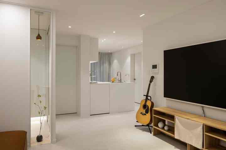 白と木目調が調和したアパートのリビングとキッチン、シンプルモダンでナチュラルな雰囲気のあるインテリア