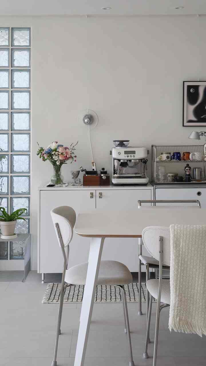 白を基調としたリビング兼おうちカフェ、コーヒーマシンとシンプルなダイニングテーブル・チェアが配置されたモダンで清潔感のあるインテリア