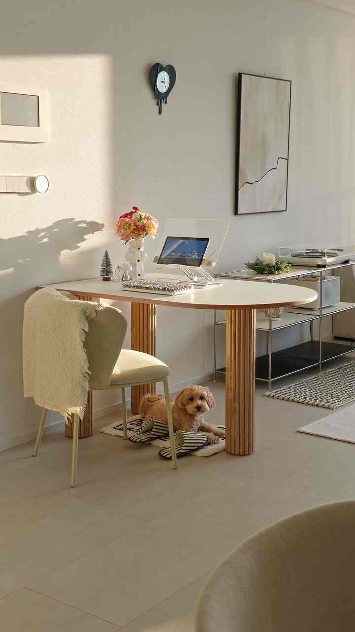 白と茶色のトーンのリビング、円形テーブルと椅子、犬がくつろぐシンプルでナチュラルな雰囲気のインテリア