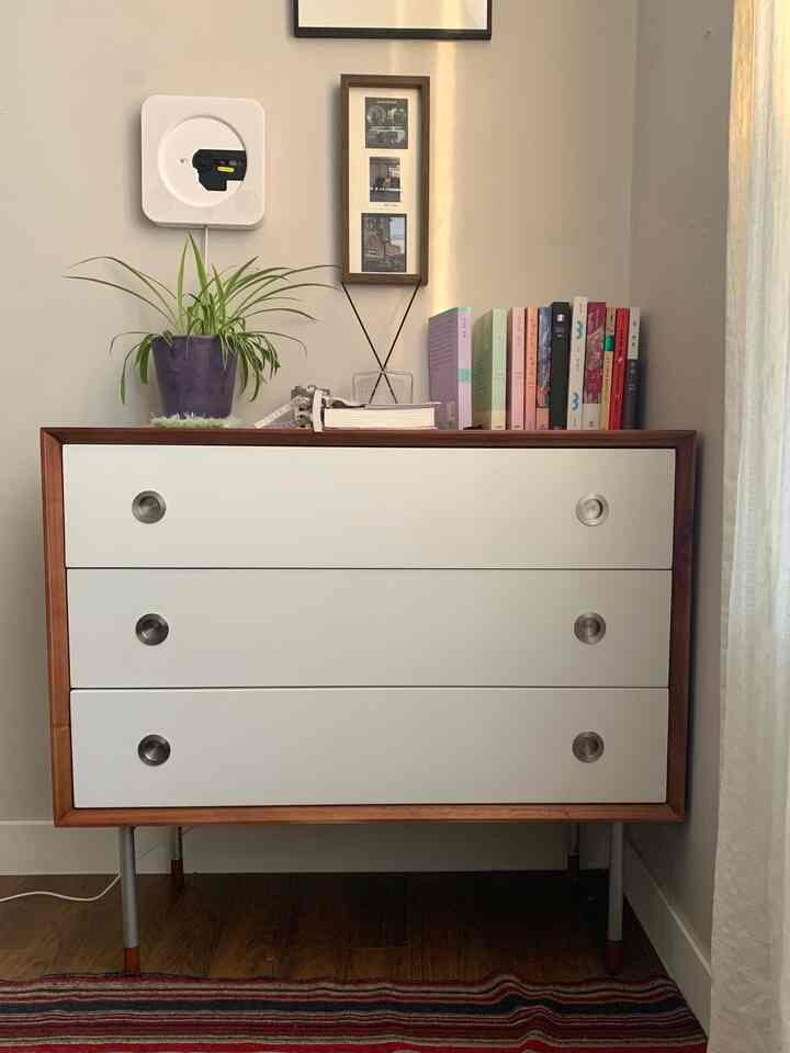 白とブラウンの木目調で構成されたコンパクトな玄関、シンプルで自然な雰囲気のドレッサーに本と植物、ディフューザーが配置されたインテリア