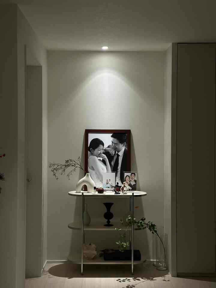 白を基調とした狭い玄関スペースに、花瓶やオブジェが並ぶシンプルなインテリア