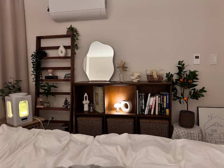 温かみのあるウォールナット調の木製家具が配置された寝室、個性的な形の卓上ミラーと多様なオブジェが調和した雰囲気のあるインテリア