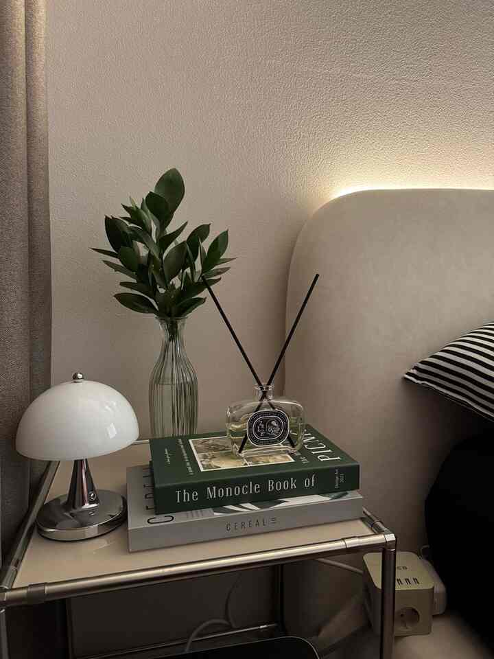 ベージュトーンの寝室、サイドテーブルに花瓶とディフューザーが配置されたシンプルでミニマルな雰囲気のインテリア