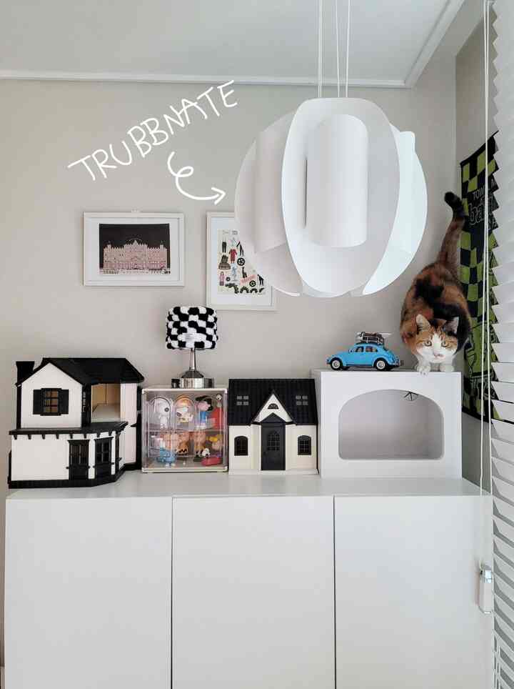 白とグレーのトーンの部屋、モダンな収納家具の上に猫とペットハウスが配置された雰囲気のあるインテリア