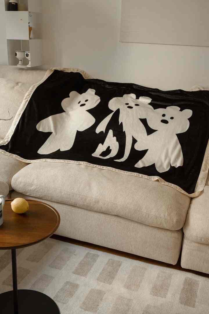 Beige tone living room featuring a beige sofa with a black and white bear blanket draped over, creating a cozy atmosphere