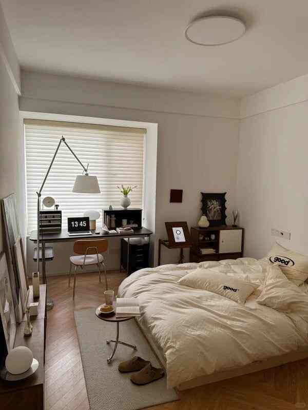 ベージュとブラウンの落ち着いた色調の寝室、ベッドと作業デスクが配置された自然で温かみのあるインテリア