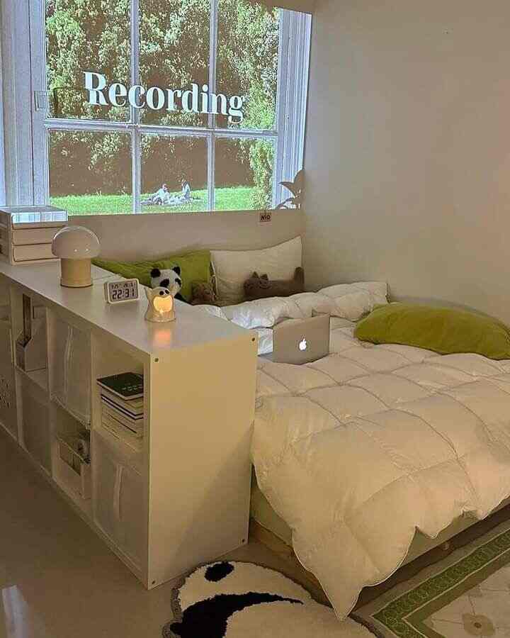 ライトグリーンとホワイトのトーンの低い寝室、ベッドと本棚が配置された雰囲気のある空間