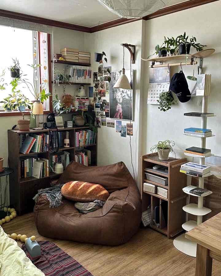 ナチュラルな木目調とホワイトの壁が印象的な居心地の良い小さな部屋、ビーンバッグと本棚が配置された読書空間