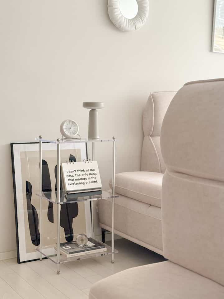 White and beige toned bedroom featuring transparent acrylic modular shelf and beige sofa with clean modern vibe