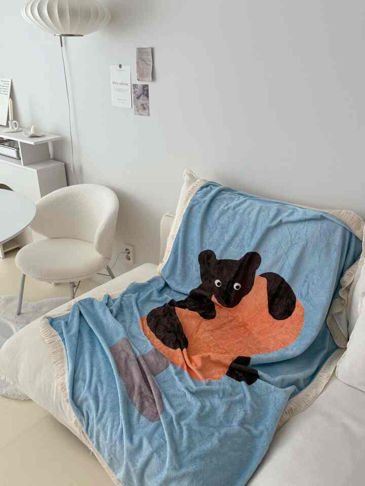 Natural white-toned living room featuring a soft sofa covered with a blue animal-themed blanket, creating a cozy atmosphere