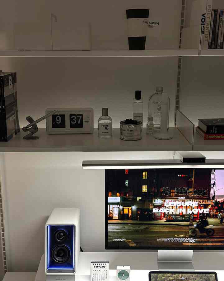 白を基調としたホームオフィス、整然としたデスクにモニター、スピーカー、フリップ時計が配置されたミニマルなインテリア