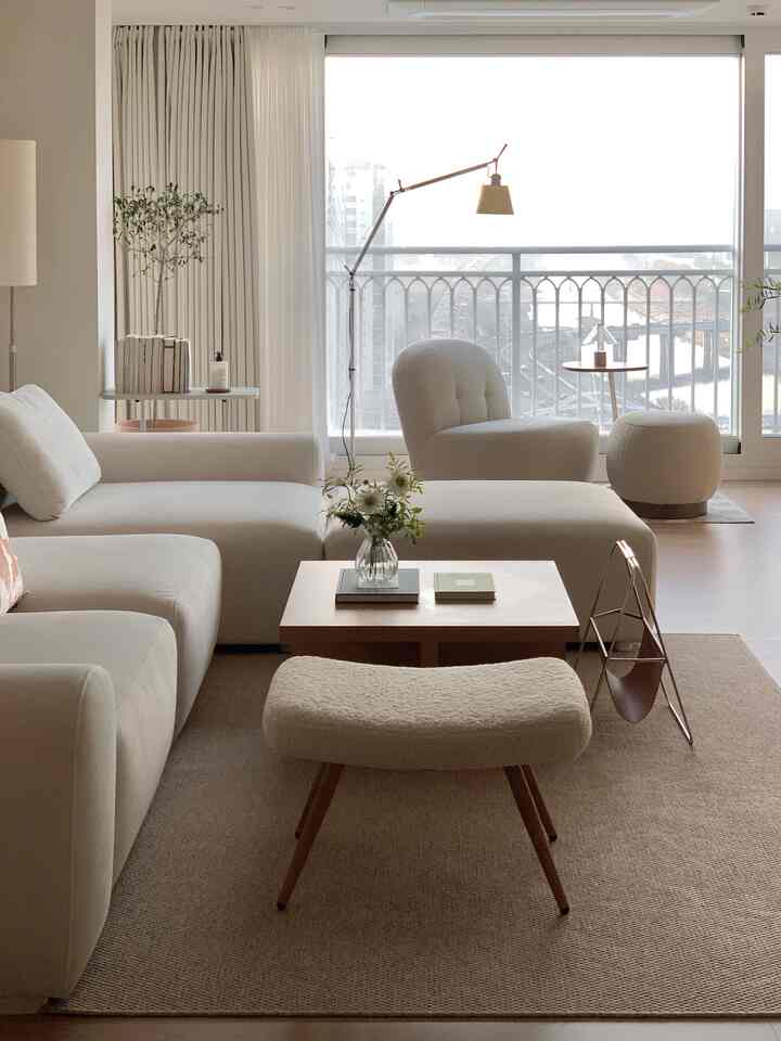 Subtle beige toned living room with bouclé sofa, lounge chair, stool, and wood coffee table creating a cozy atmosphere