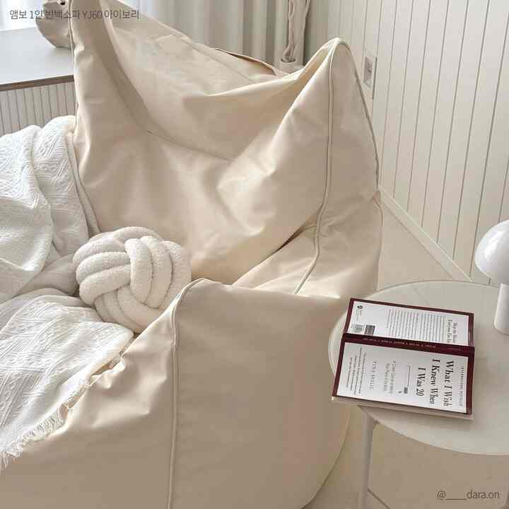 Ivory-toned studio living room featuring a cozy bean bag sofa with a white side table, creating a warm and relaxing atmosphere