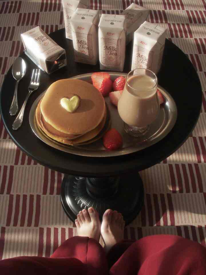赤と黒の色調の丸いコーヒーテーブルにパンケーキ、イチゴ、ミルクティーが配置された雰囲気のあるおうちカフェ空間