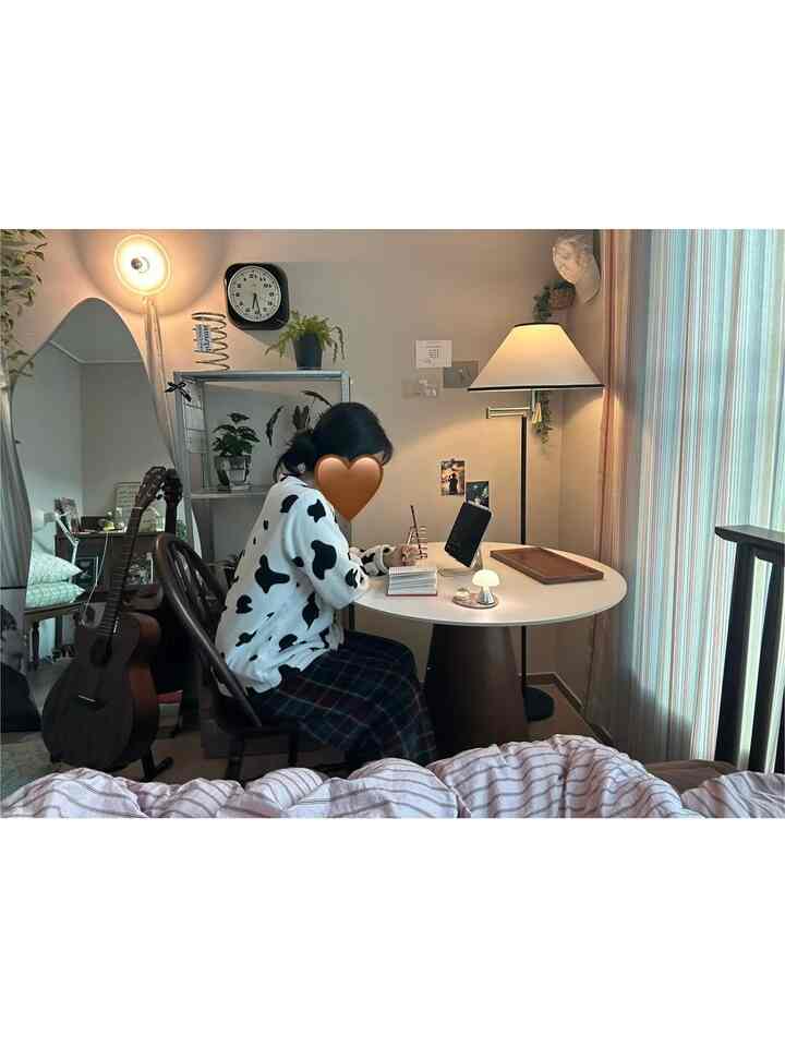 白と茶色のトーンの寝室、丸テーブルと椅子、フロアランプが配置された雰囲気のあるホームオフィススペース