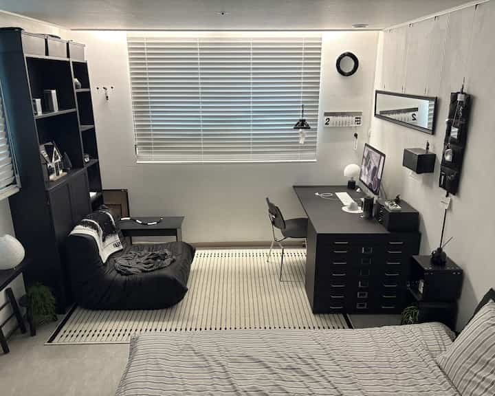 A long and narrow 5-pyeong bedroom in black and ivory tones, featuring a desk and sofa in a modern and tidy space