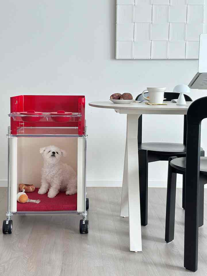 White and red toned dining area featuring a dog in a pet house next to the table in a clean, minimal space