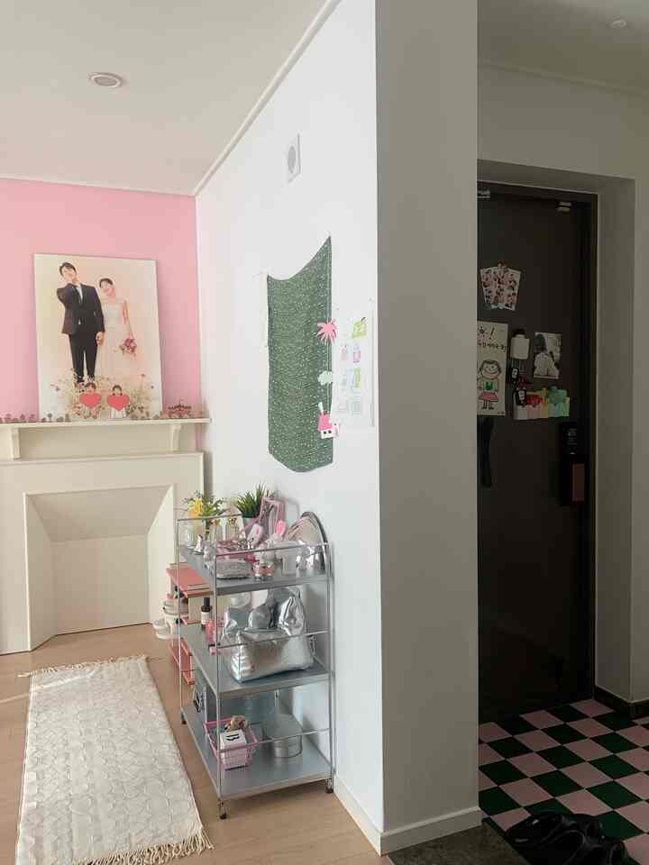 ピンクとグリーンの色調の玄関、シルバーの棚と整理された小物が配置されたモダンな雰囲気のインテリア