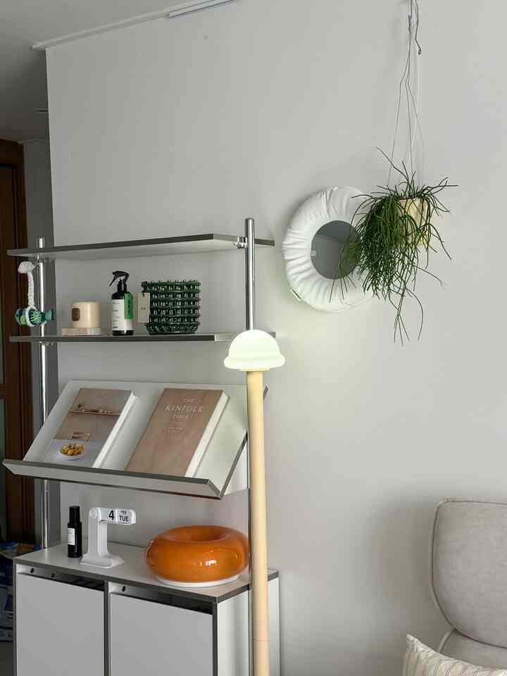 白とベージュのトーンのリビング、フロアランプと実用的な収納が配置された雰囲気のあるインテリア