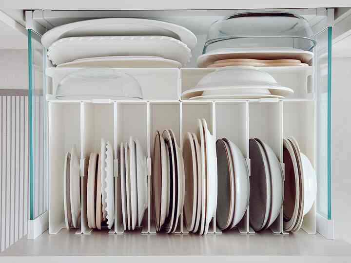 White-toned pantry storage space featuring neatly organized plates with storage ideas in a clean kitchen interior