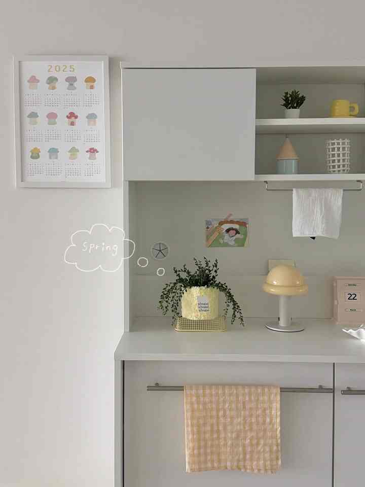 白とナチュラルカラーが調和したキッチン、清潔感のある収納と造花が配置されたシンプルで落ち着いたインテリア