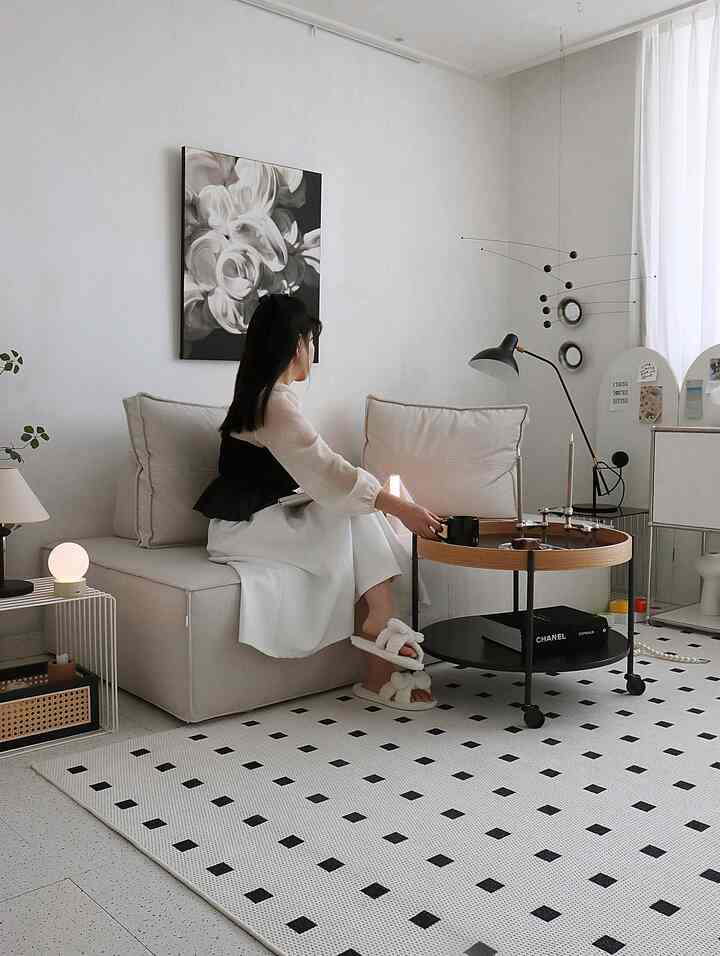 ホワイトとライトブラウンの色調のリビング、ベージュのソファと円形のコーヒーテーブル、パターンラグが配置されたシンプルな空間