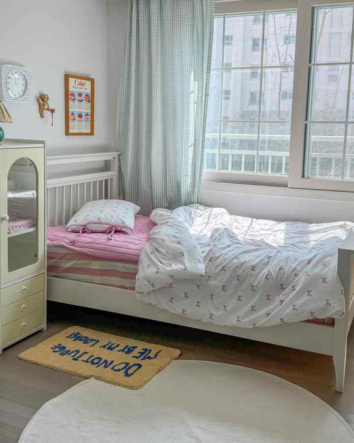 ホワイトとピンクのトーンの子供部屋、リボン柄の寝具とホワイト家具が配置された雰囲気のあるインテリア