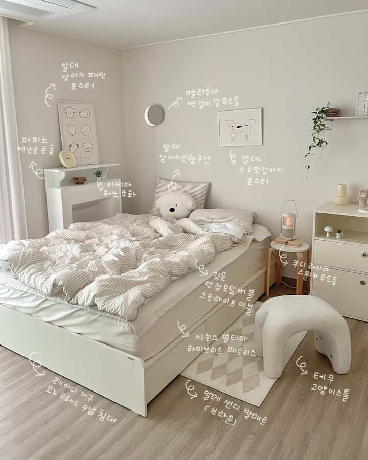 アイボリーとホワイトの色調の寝室、白いベッドとチェスト、犬のポスターやクッションが配置された雰囲気のあるインテリア