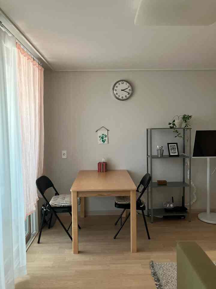 白とナチュラルの色調のダイニングルーム、中央に木製テーブルと2つの折りたたみ椅子が配置された清潔感のある空間