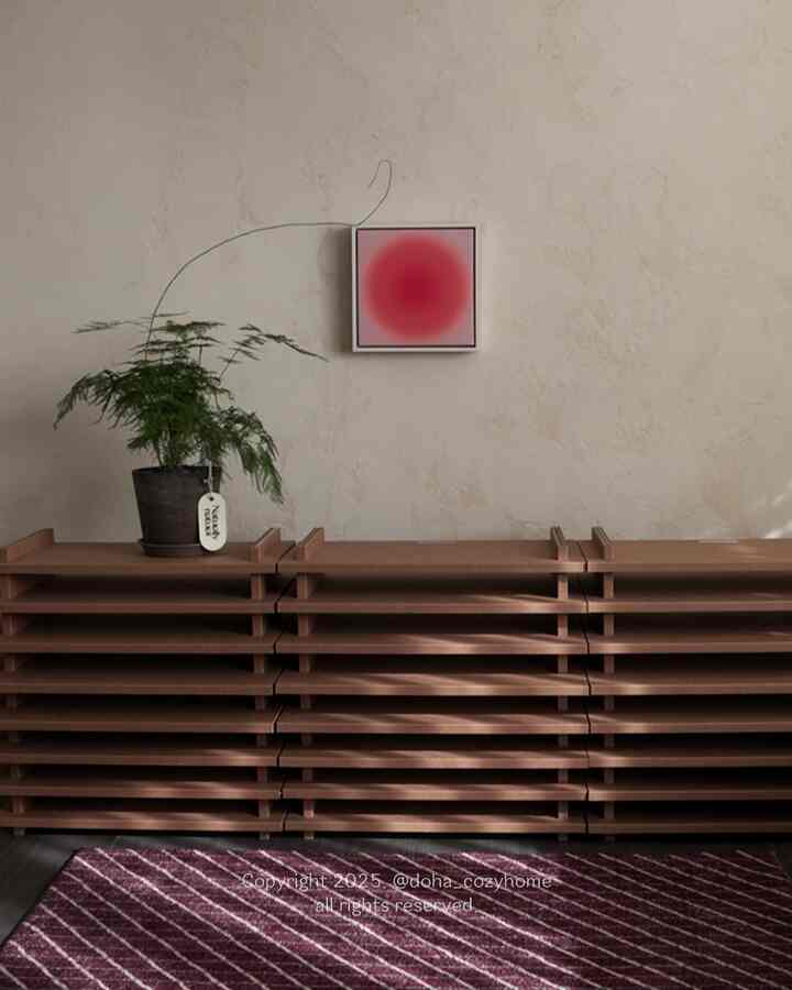 Minimal modern entrance with beige walls and brown shelves, featuring a red circular wall art and a green plant as focal points