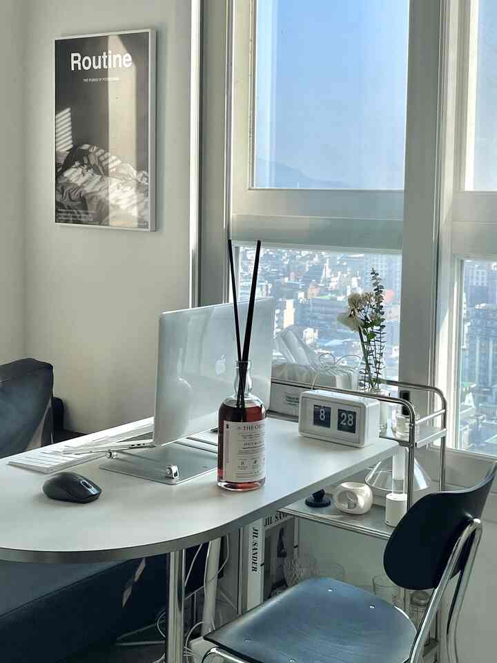 ホワイトトーンのホームオフィス、シンプルなデスクとブラックチェアが配置された清潔感のある作業空間