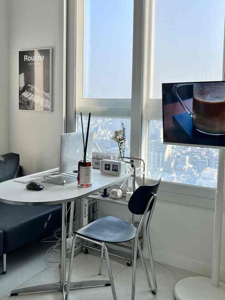 ホワイトとブラックのトーンのモダンなリビングルーム、ホームオフィスのデスクとソファ、ウイスキーディフューザーを配した空間