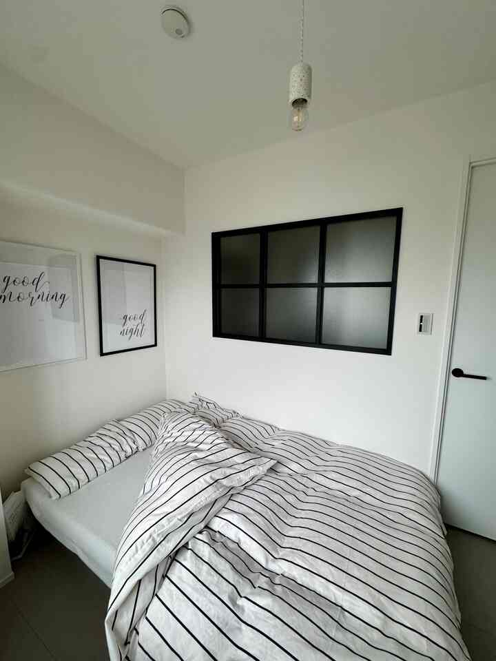 白と黒の寝室、ストライプの掛け布団と額装されたアートが配置されたシンプルモダンな雰囲気のあるインテリア