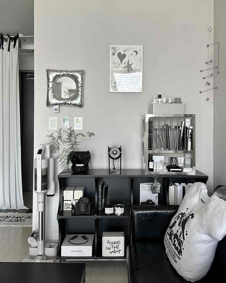 Monotone-toned living room featuring a black sofa, shelf unit, silver mobile, and framed art creating a modern atmosphere
