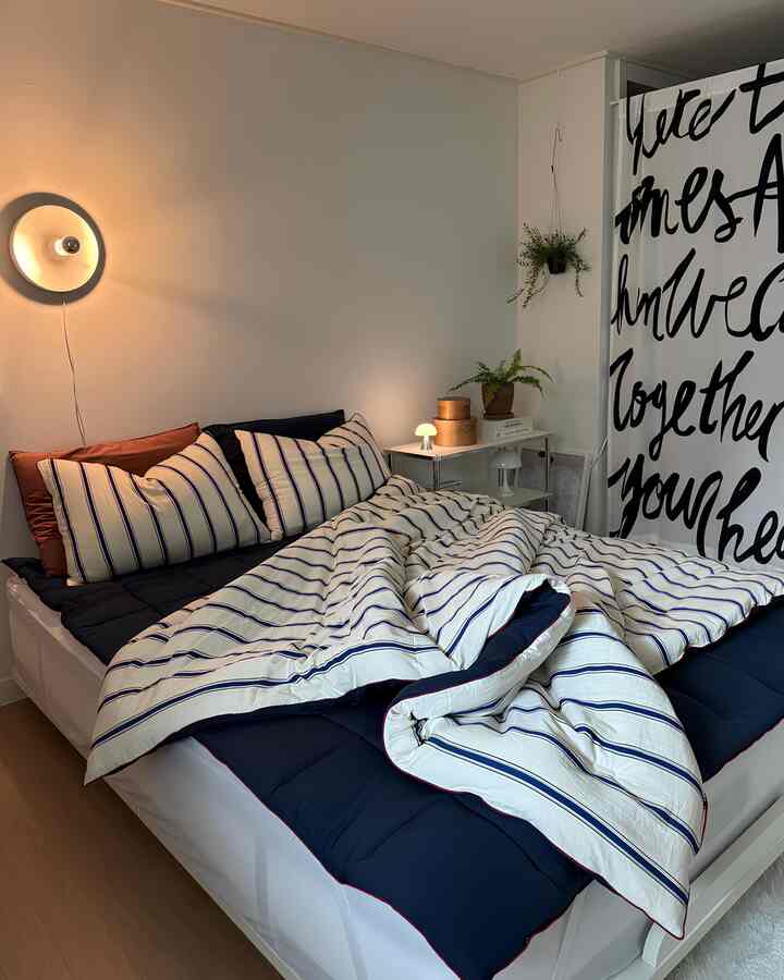 White and navy toned bedroom featuring striped bedding and pillows with a cozy atmosphere