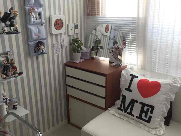 ベージュとホワイトトーンの狭い部屋、キャラクターフィギュアと化粧台が配置された雰囲気のあるインテリア