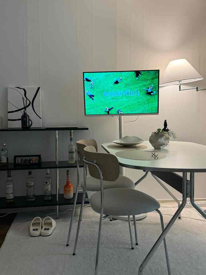 White-toned two-person dining area with dining table, chairs, and home bar shelving in a simple modern interior