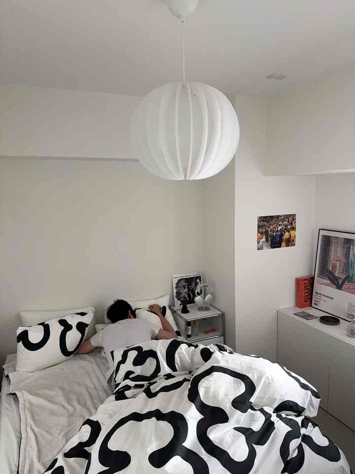 白と黒のパターンが特徴のモダンな寝室、中央にベッドとペンダントライトが配置された雰囲気のあるインテリア