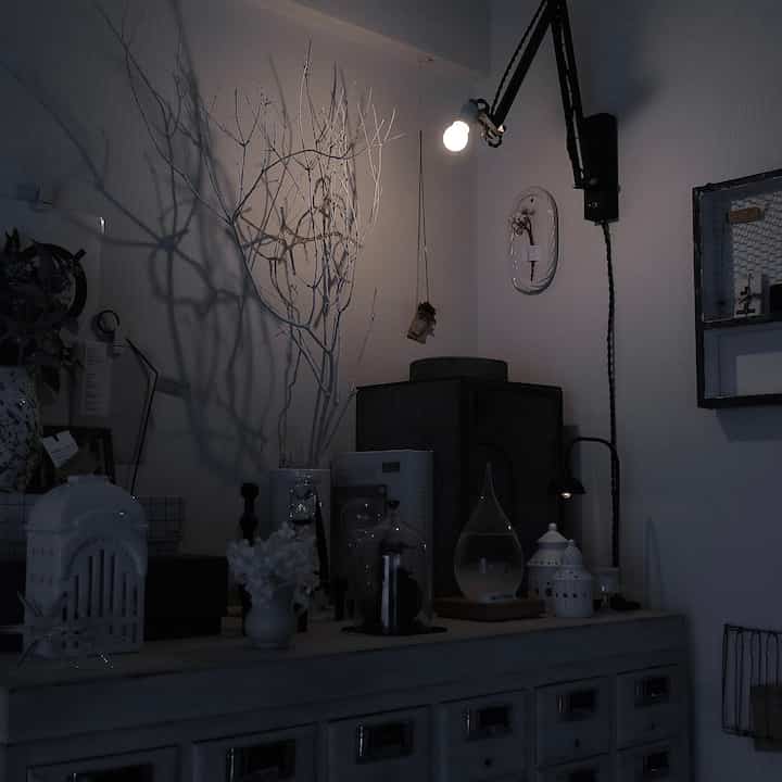 Monotone-toned living room corner featuring wall-mounted lamp and decorative objets creating a cozy ambiance