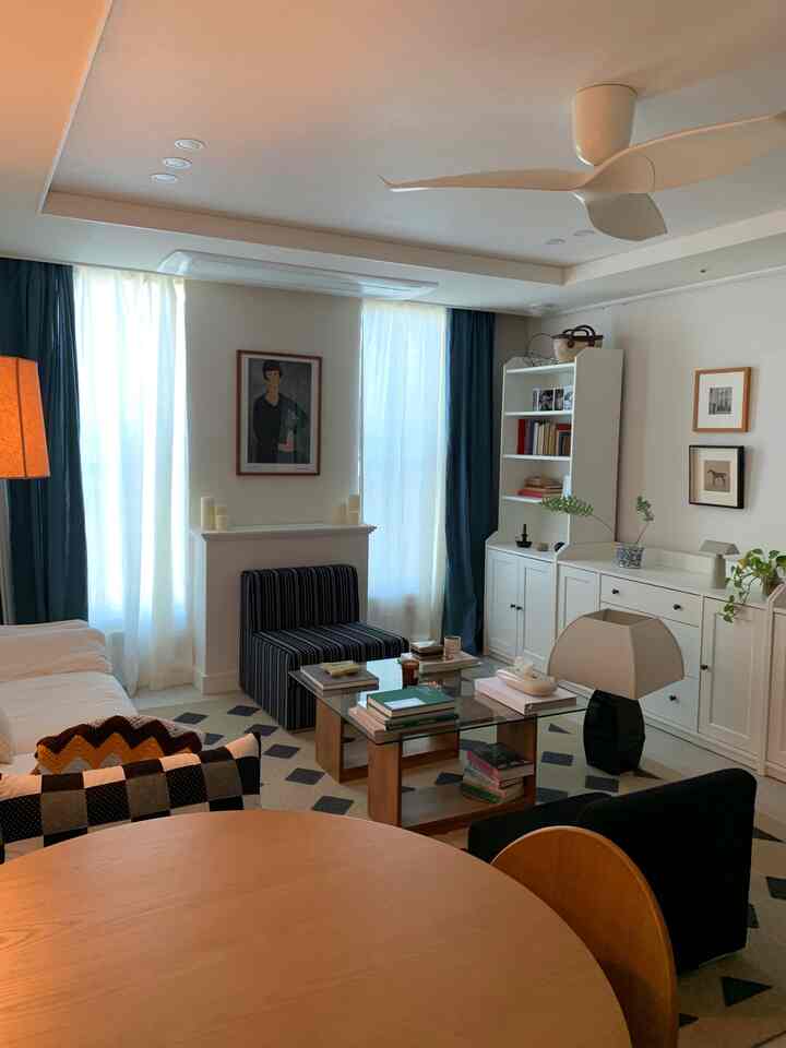 白とダークブルーのカーテンがあるリビングルーム、木製のダイニングテーブルとガラスのコーヒーテーブルが配置された落ち着いたモダンな雰囲気のインテリア